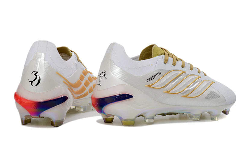 Adidas Predator x Elite FG white and gold soccer cleats with textured upper and studded sole, designed for performance on the field.